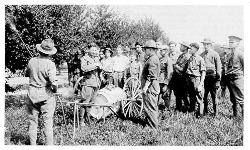 old black and white photograph of students spraying fruit trees. 